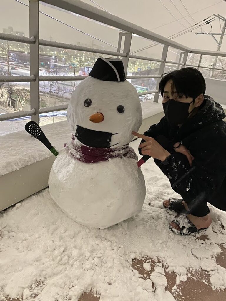 Донгвон из KNK нарядил снеговика в шапку, шарф и маску, а сам сидит почти босиком 😬